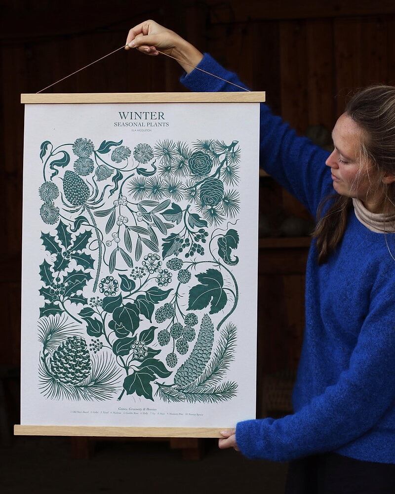 Printmaker holding a print of winter plants.