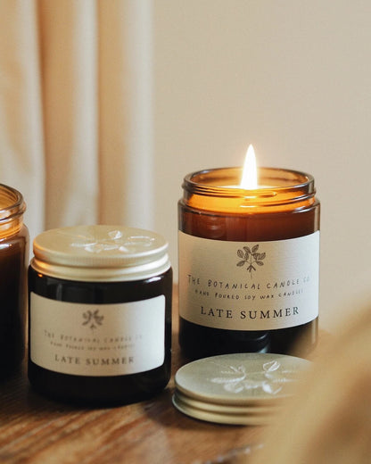 Candle labeled 'Late Summer' from The Botanical Candles Co. on a wooden surface with a neutral background.