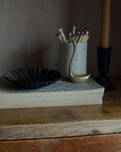 A metal incense holder in a fluted circle design, with a bronzed finish.