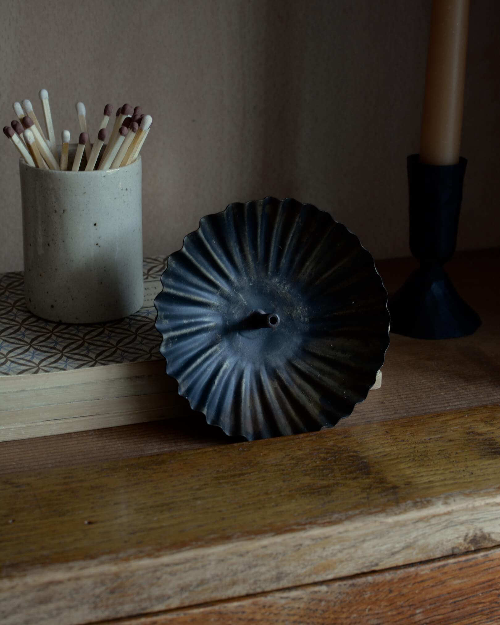 A metal incense holder in a fluted circle design, with a bronzed finish.