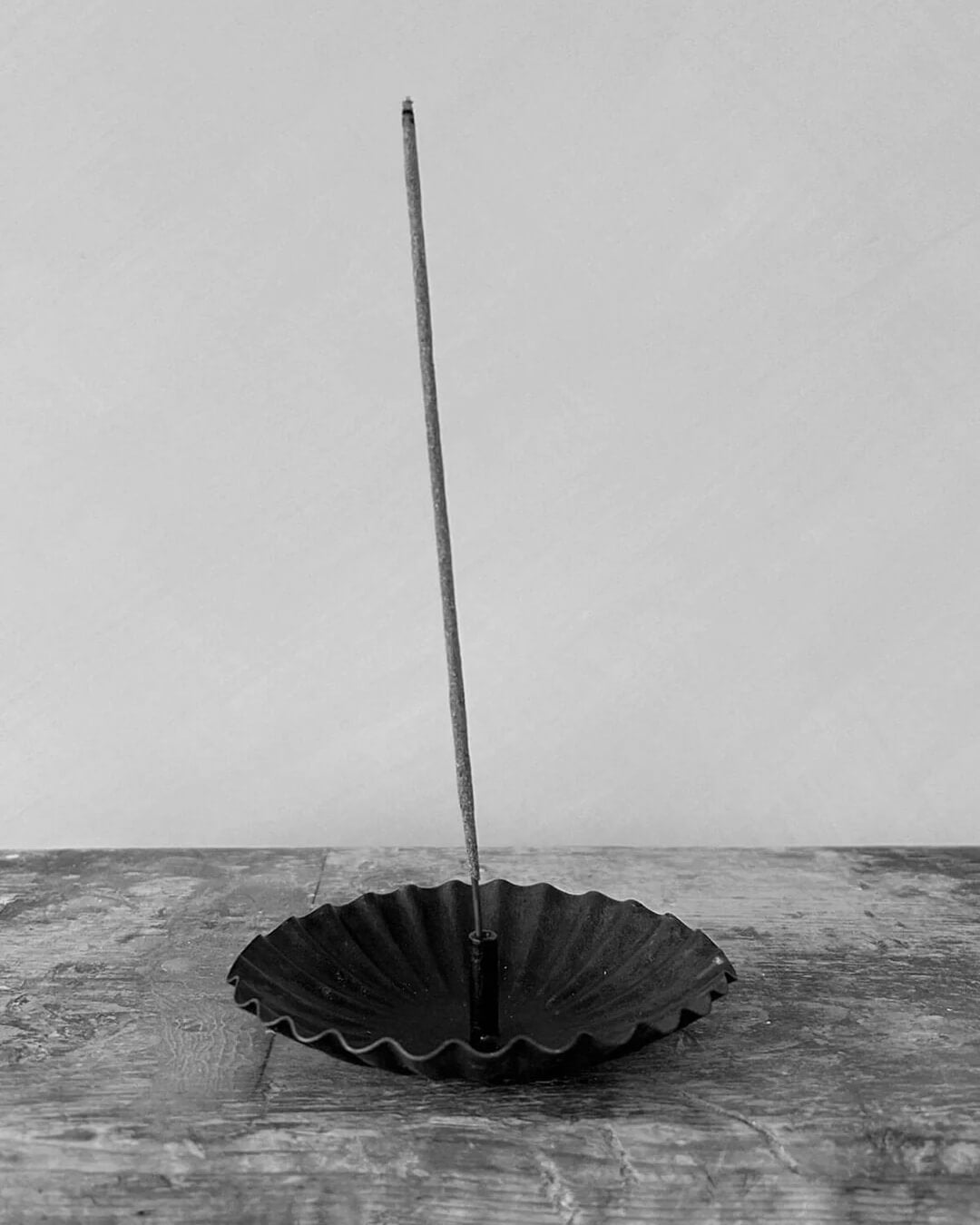 A metal incense holder in a fluted circle design, with a bronzed finish.