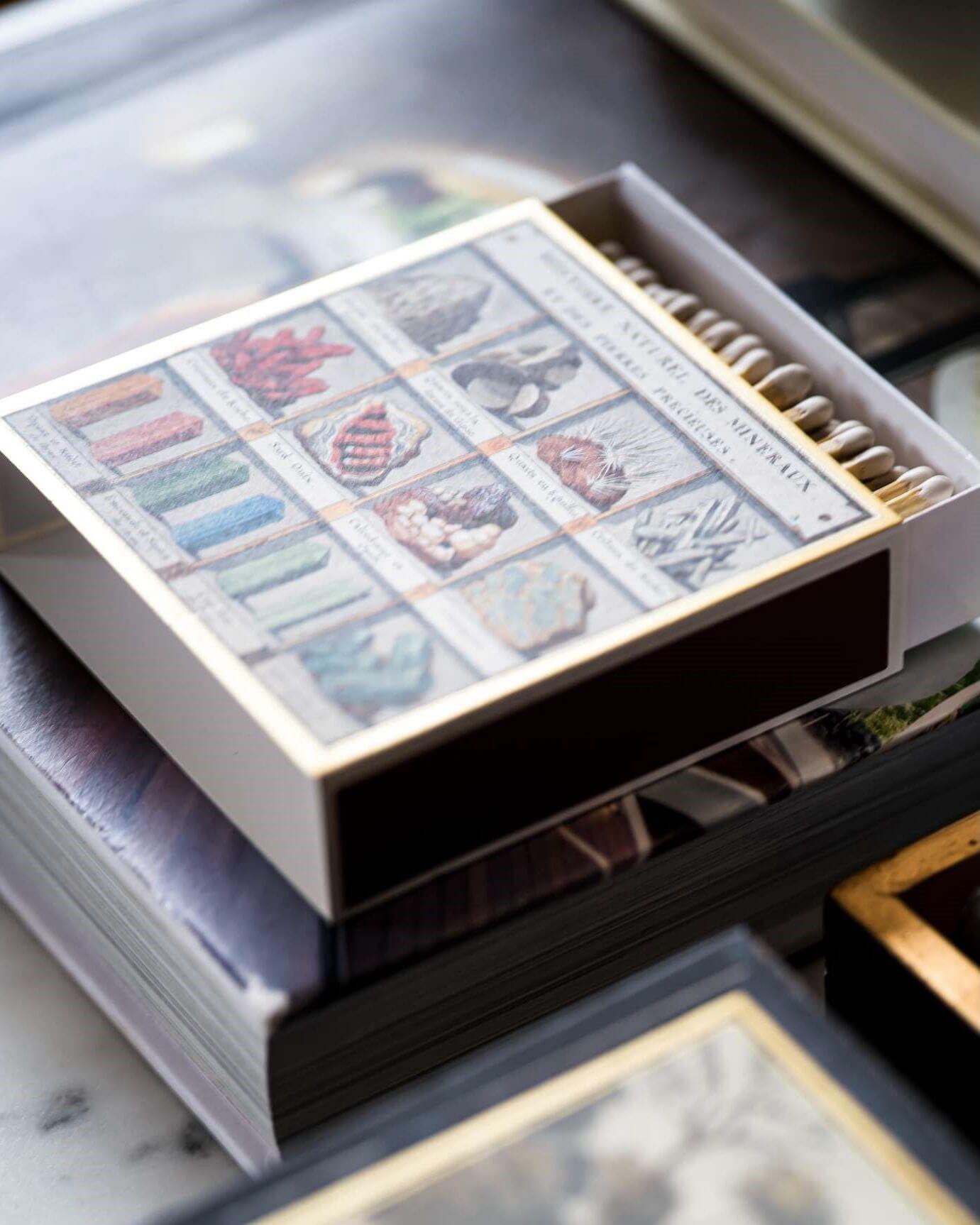 Illustrated box of matches, stacked on top of books on a desk.