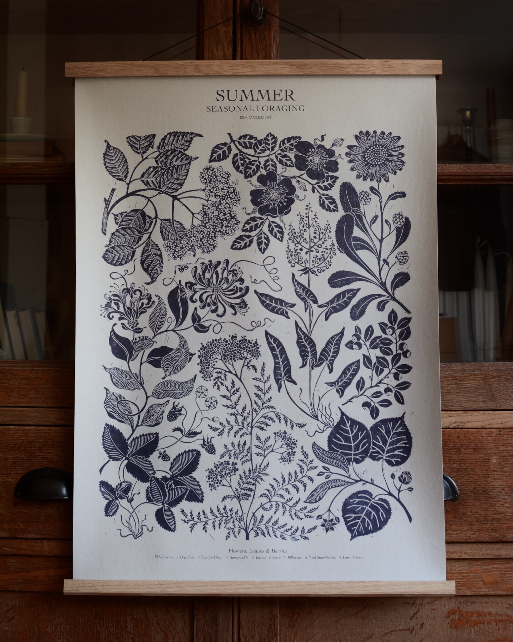 A large botanical print displayed in an oak magnetic poster hanger.