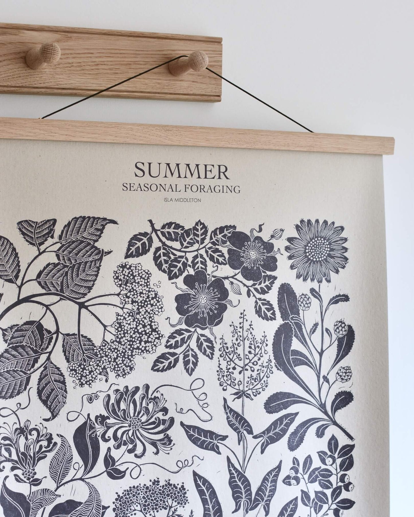 A solid oak peg rail, displaying a botanical poster.
