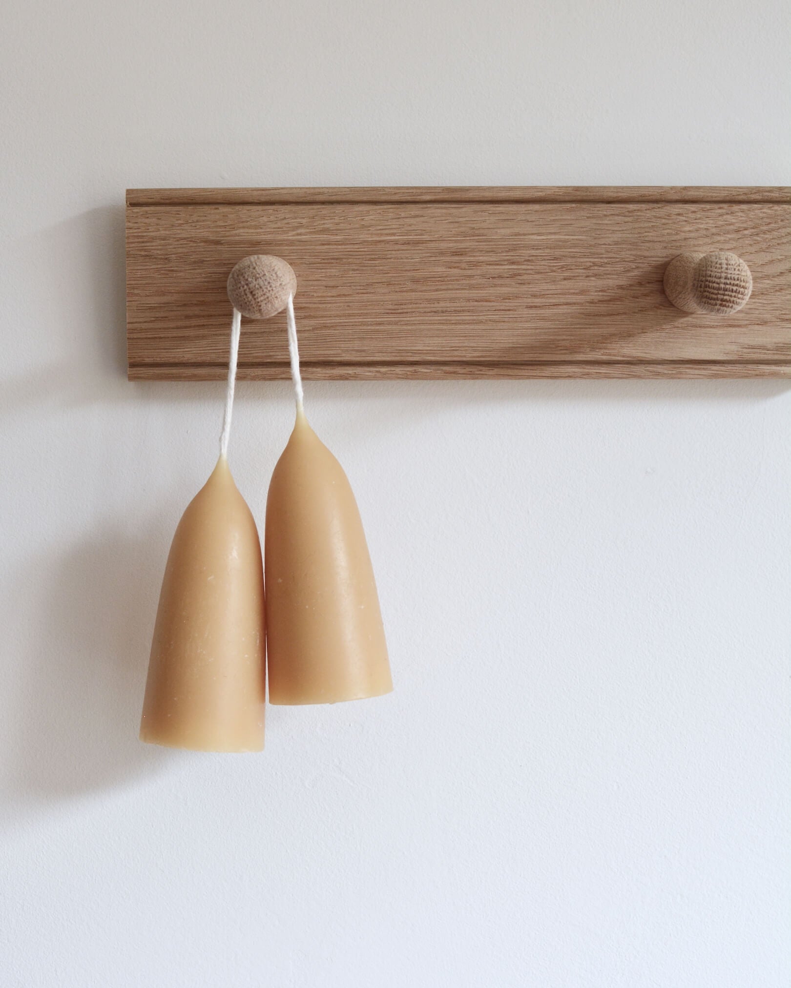 A solid oak peg rail, displaying beeswax candles.