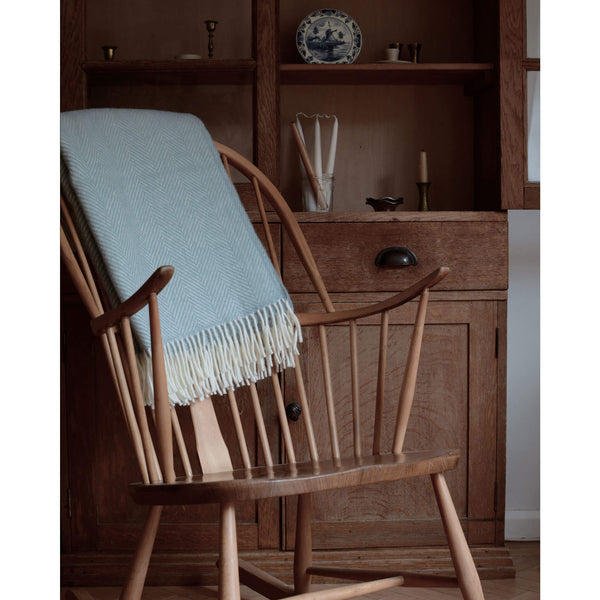 Duck egg blue wool blanket draped over back of a rocking chair.