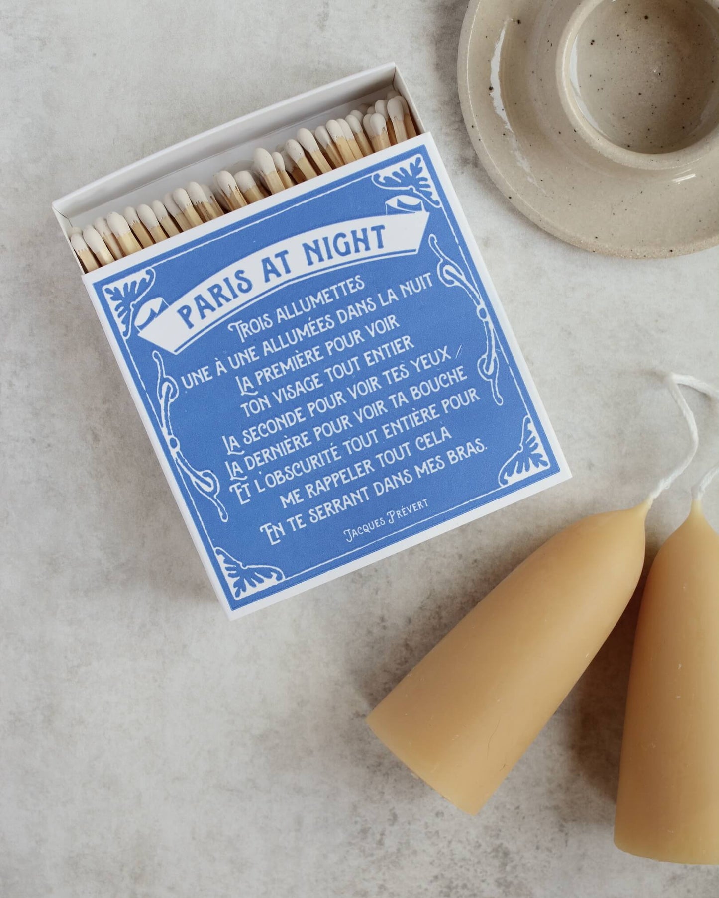 Blue and white matchbox, next to a beeswax candle and ceramic candle holder.
