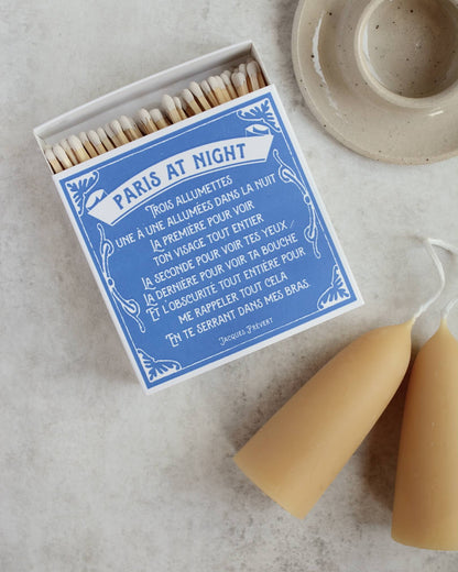 Blue and white matchbox, next to a beeswax candle and ceramic candle holder.