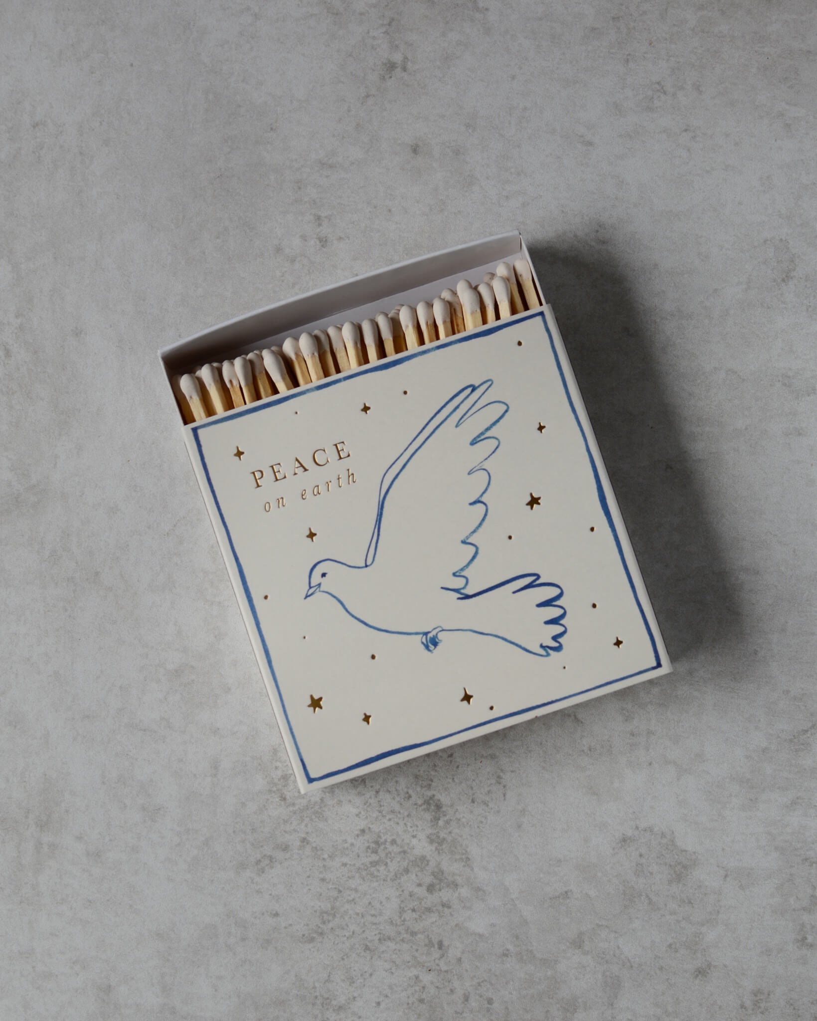 A white matchbox, with a dove illustration and 'peace on earth' lettering.