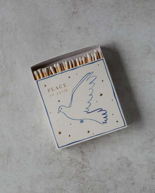 A white matchbox, with a dove illustration and 'peace on earth' lettering.