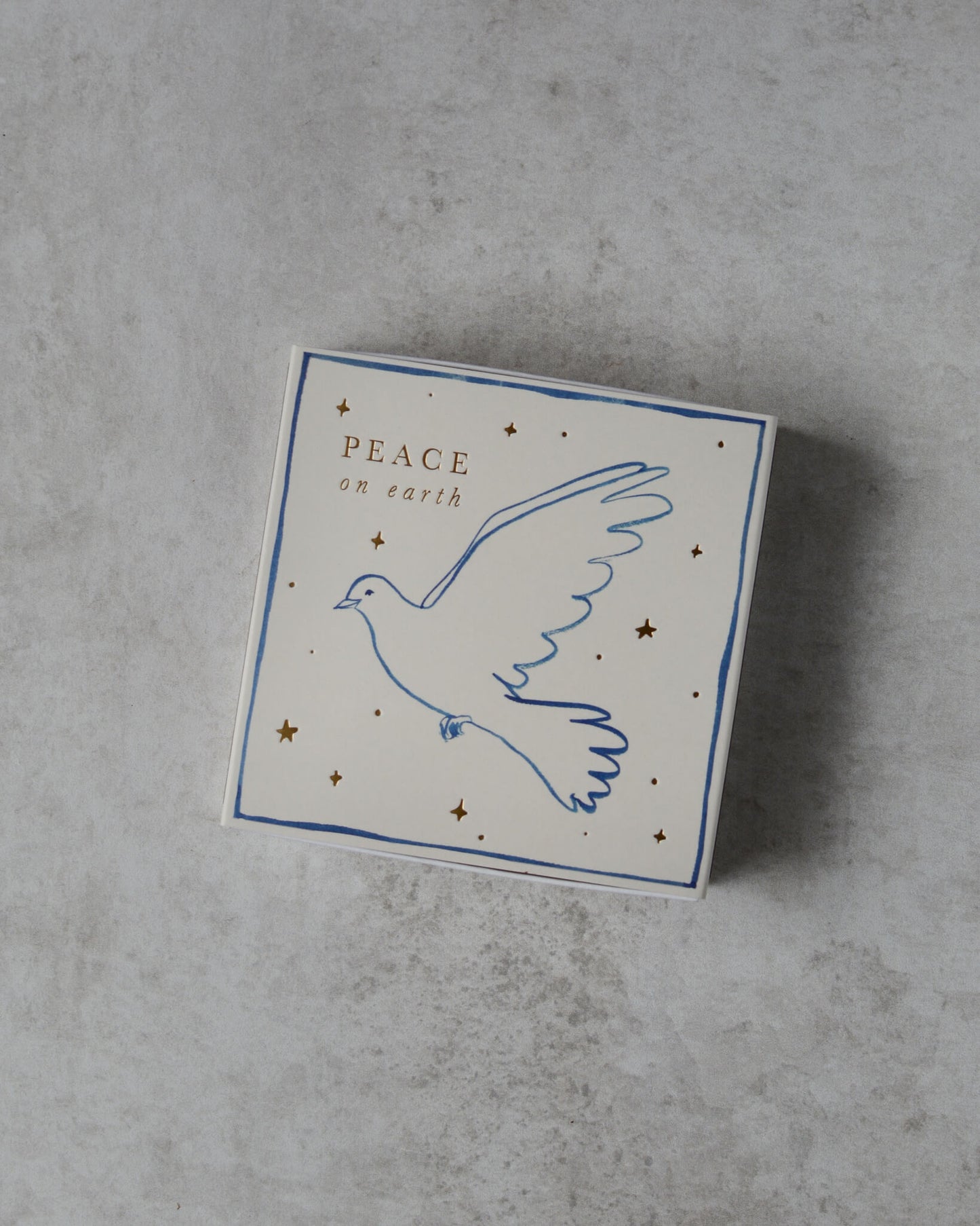 A white matchbox, with a dove illustration and 'peace on earth' lettering.