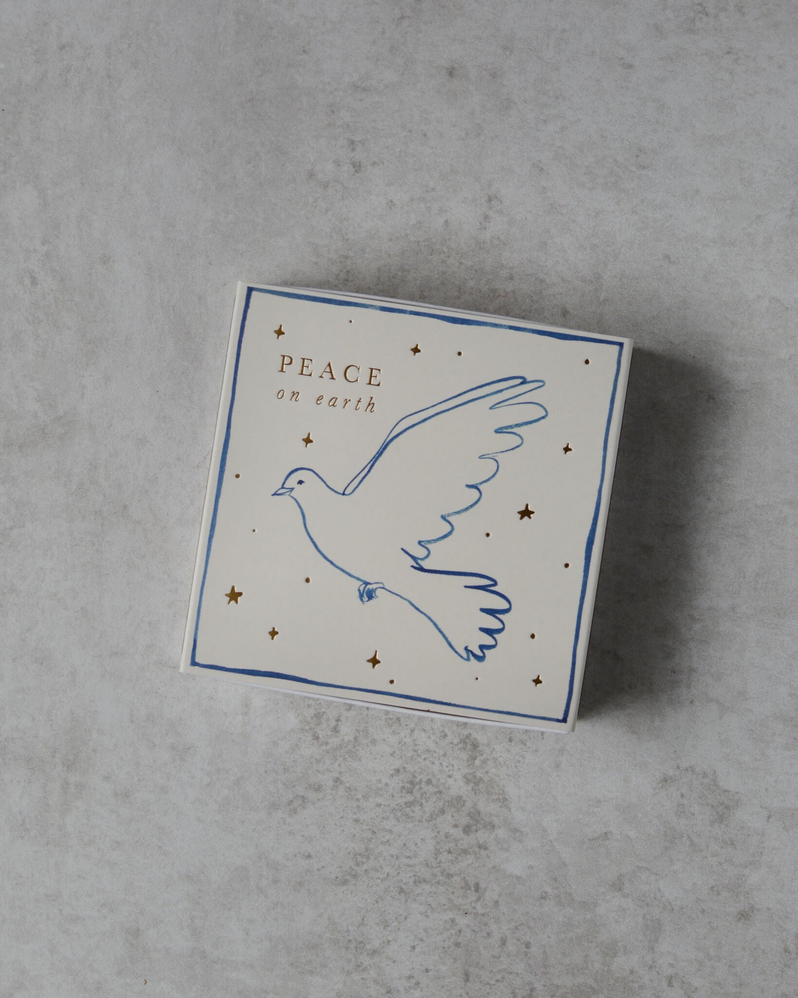 A white matchbox, with a dove illustration and 'peace on earth' lettering.