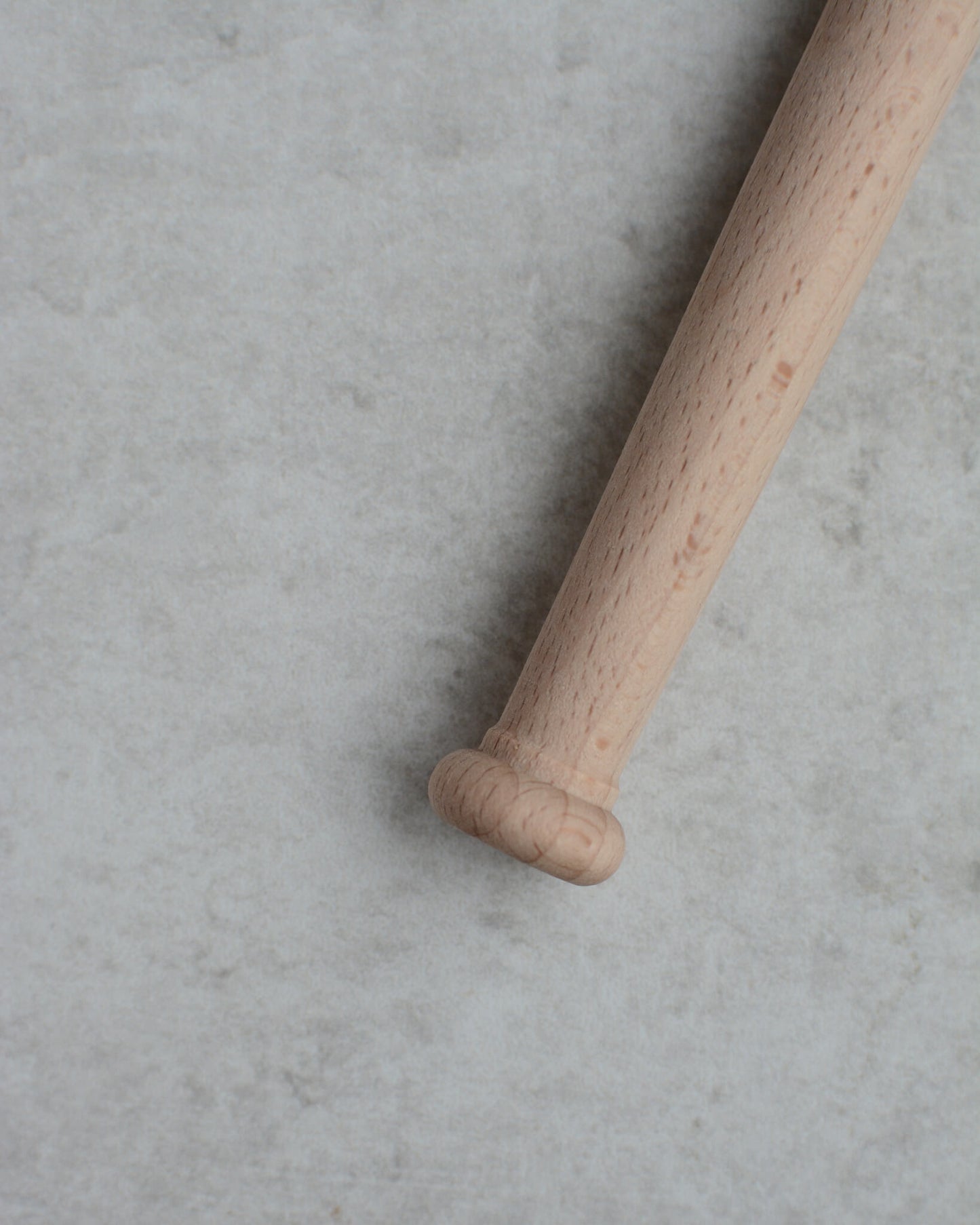 A wooden porridge spurtle, shown on a grey background.