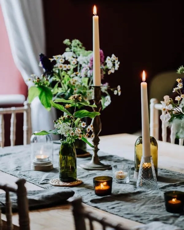 A table set for dinner, with tall taper candles displayed in glass candle holders.