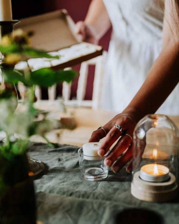 Person setting a candle on a table with a blurred background