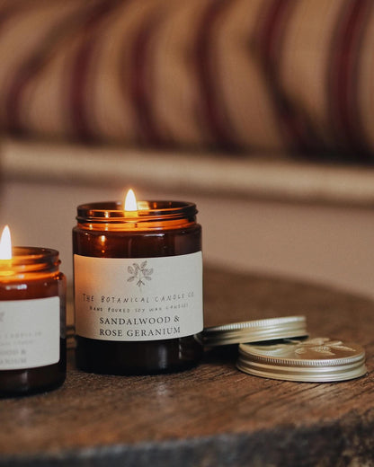 Two lit candles with labels on a wooden surface