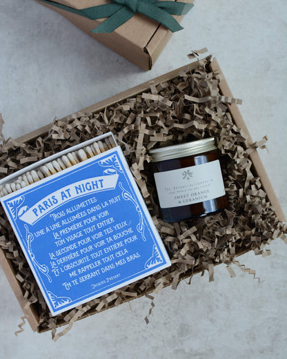 A gift box containing a glass jar candle and a box of letterpress matches.