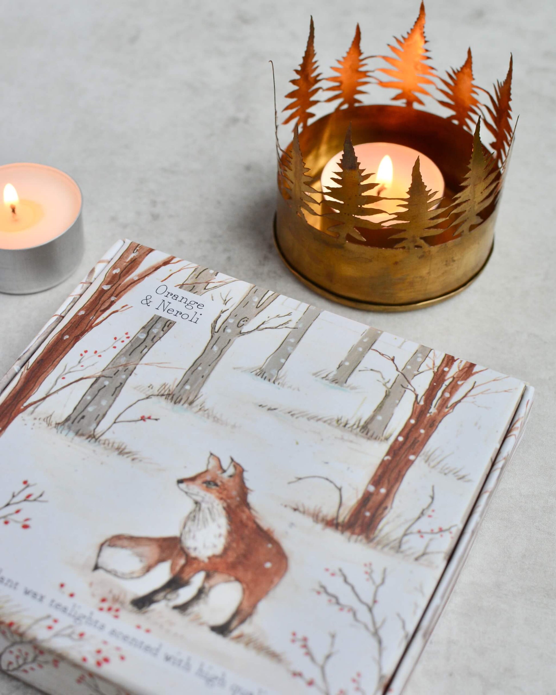Candlelit scene with a illustrated box featuring a fox illustration and a decorative metal candle holder.