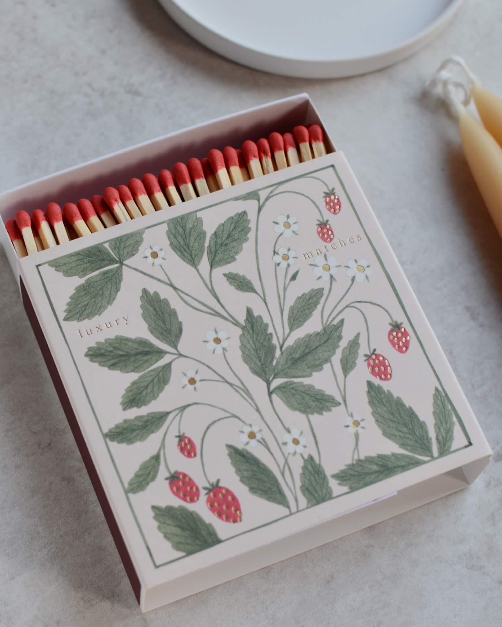 Close-up of a matchbox featuring an illustration of wild strawberries.