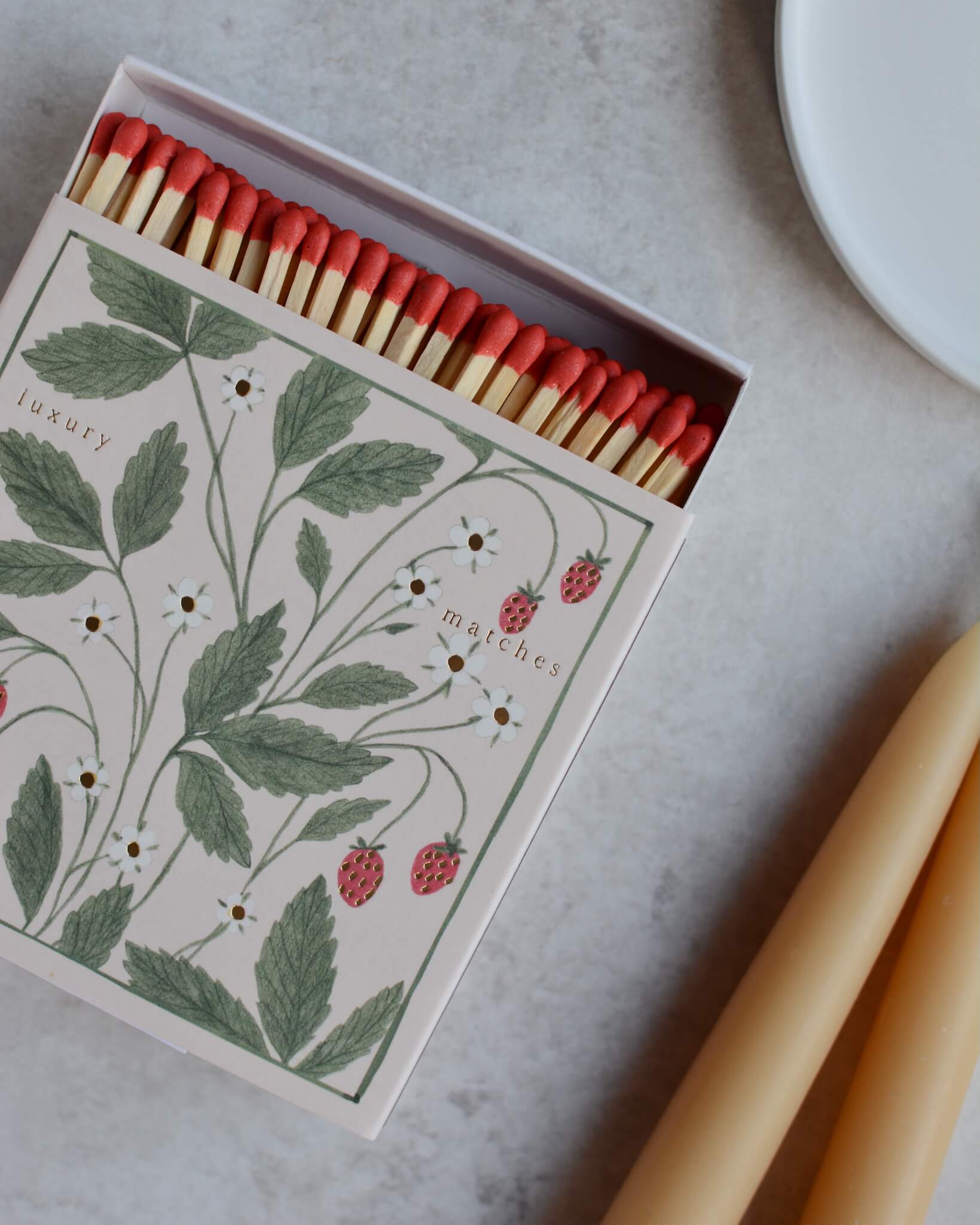 A square box of matches featuring an illustration of wild strawberries.