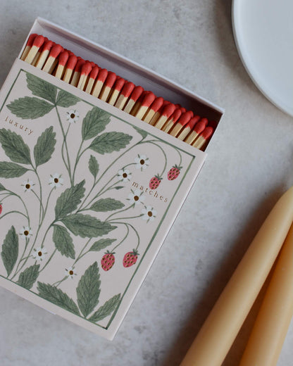 A square box of matches featuring an illustration of wild strawberries.