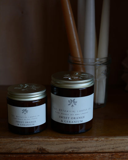 Sweet Orange and Geranium soy wax candle by The Botanical Candle Co. next to beeswax candles.