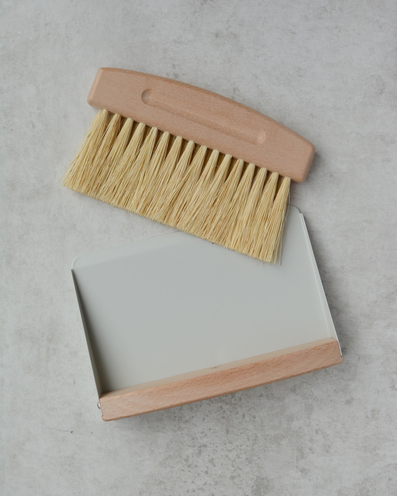 Cleaning brush with wooden handle and bristles on a gray surface
