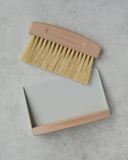 Cleaning brush with wooden handle and bristles on a gray surface