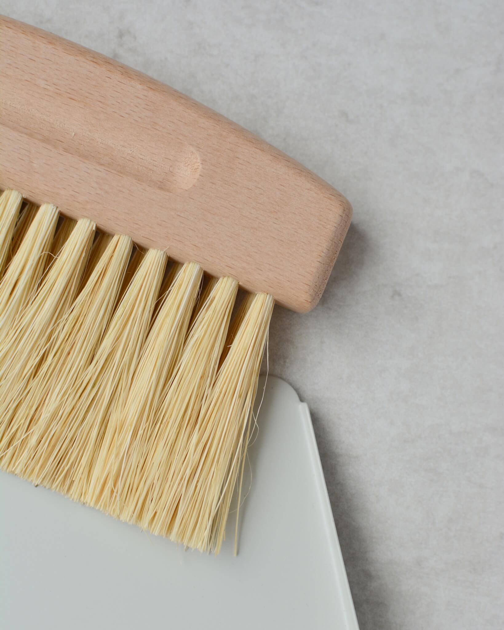 Close-up of a brush with wooden handle and bristles on a light grey background