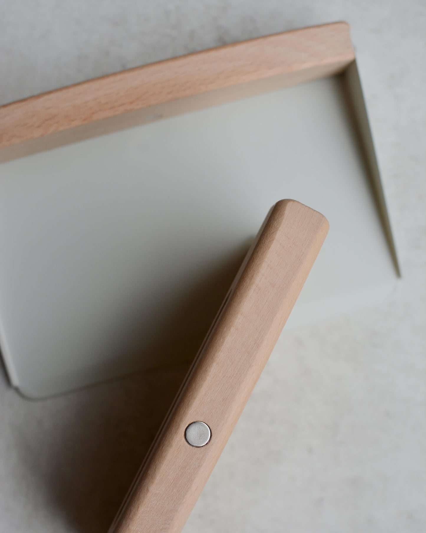 Detail photo of a small wooden and metal dustpan and brush set, showing magnetic fixing.