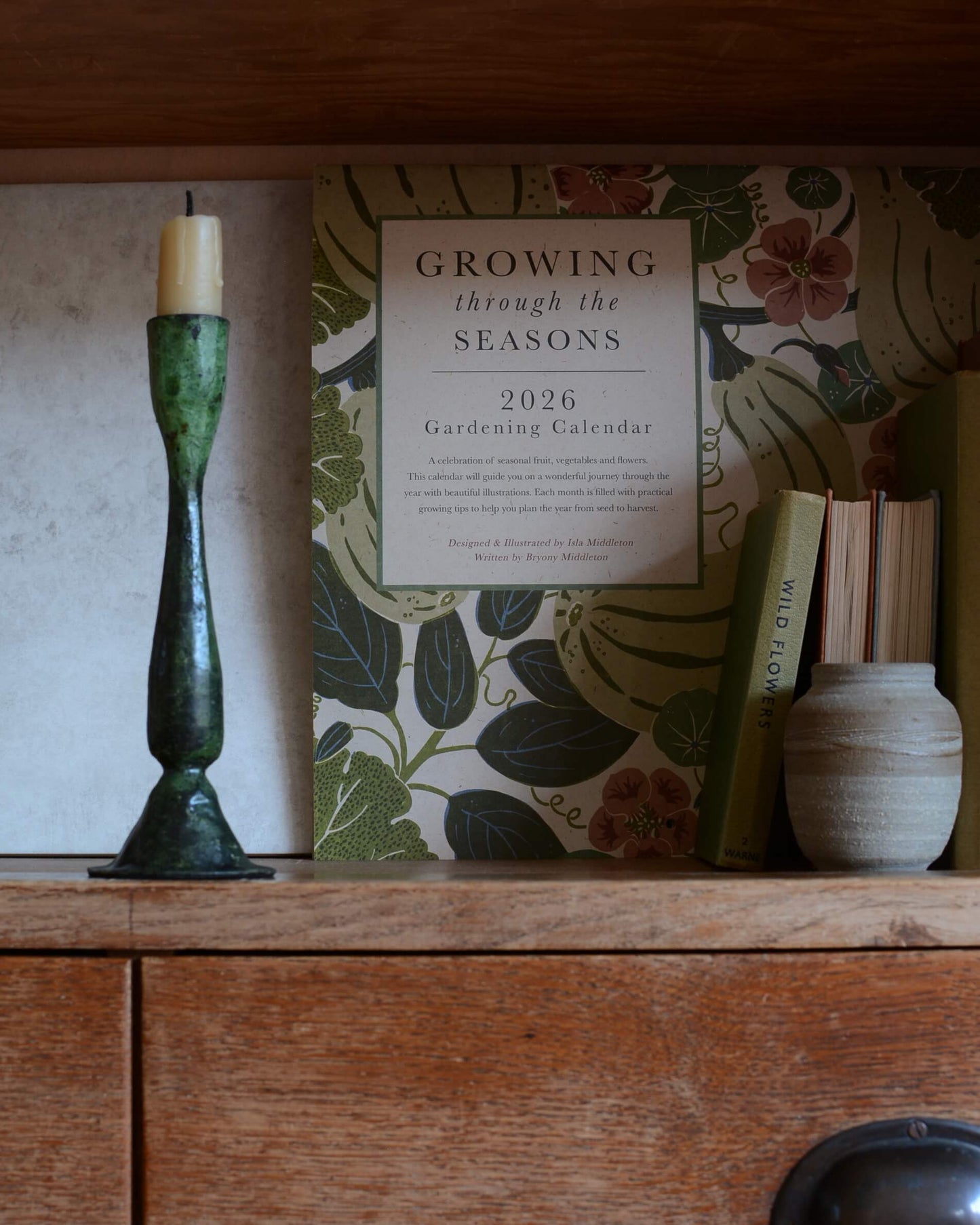 A green verdigris tall candle holder, for dinner candles, shown with a beeswax candle.