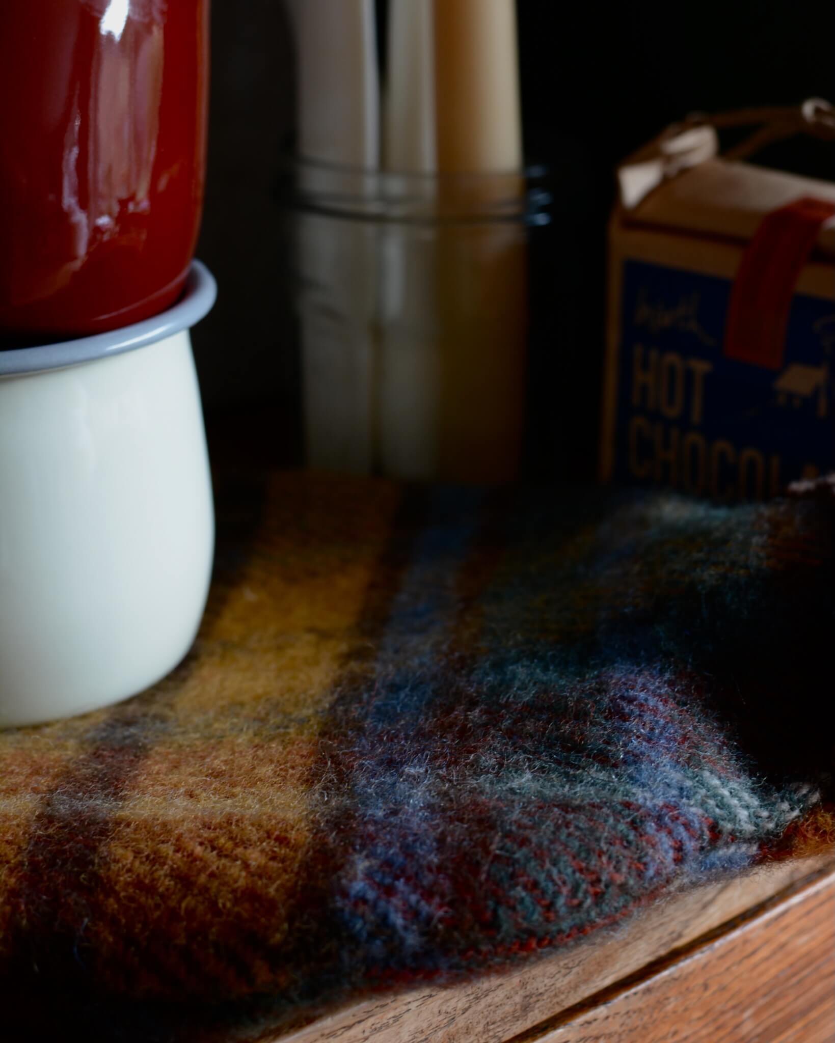 Close-up of a wool plaid hot water bottle on a wooden surface with a blurred background