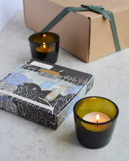 A pair of olive green tealight votives, with lit tealights.