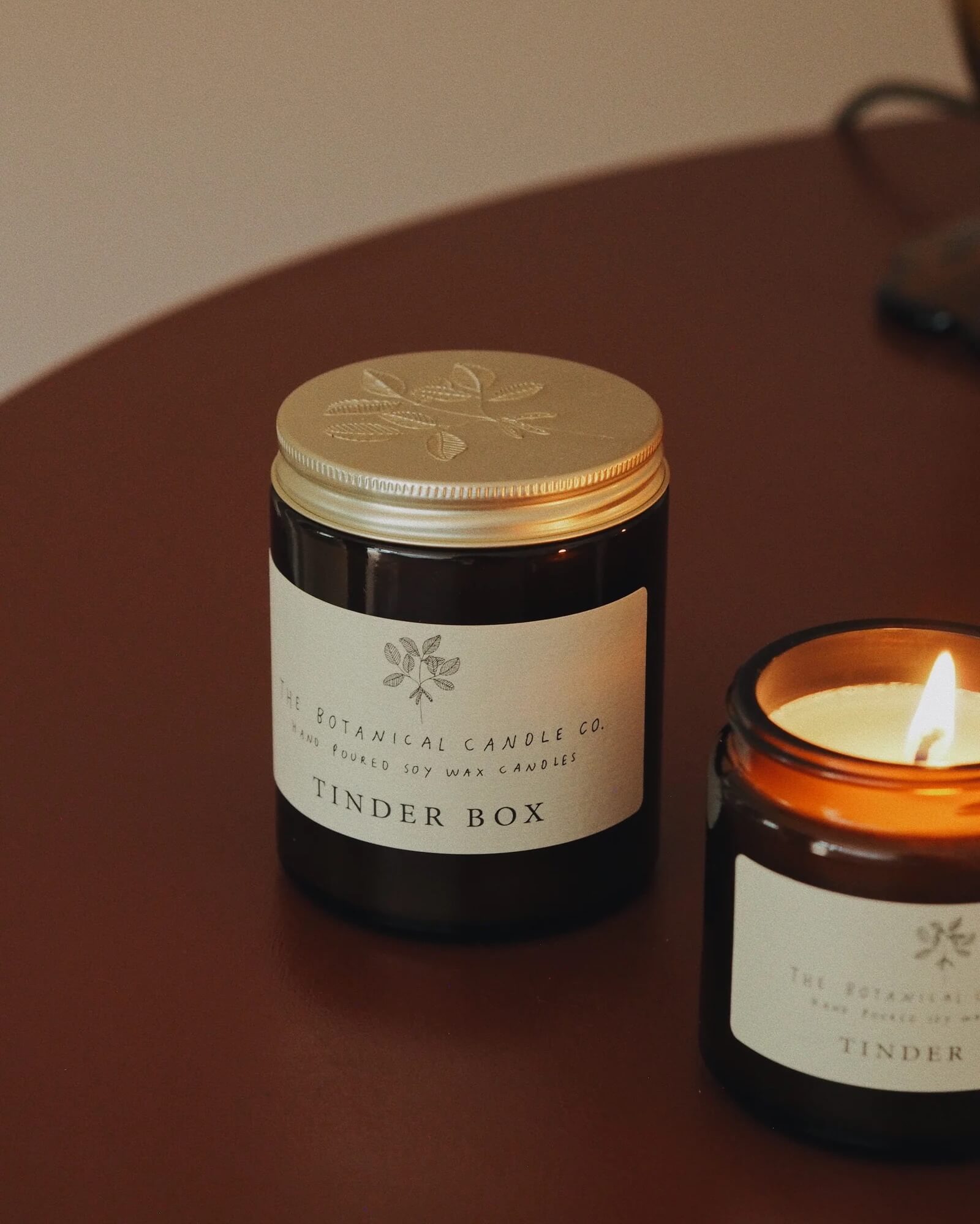 Candle jar with lid and 'Tinder Box' candle on a surface