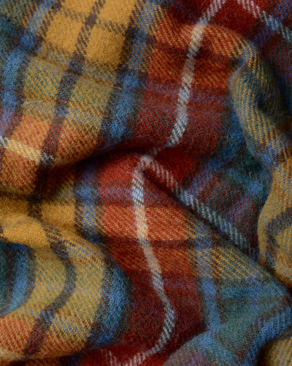 Close up of a plaid wool blanket, with tones of red, yellow and blue.