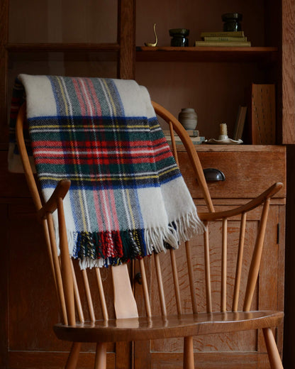 Plaid wool blanket with colourful pattern, shown on a wooden rocking chair.