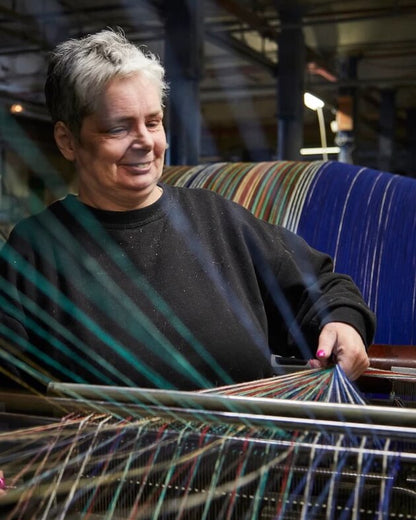 Person working with yarn on a loom at Tweedmill Textiles in Wales.