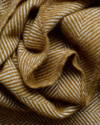 Detail of a mustard yellow wool herringbone blanket.