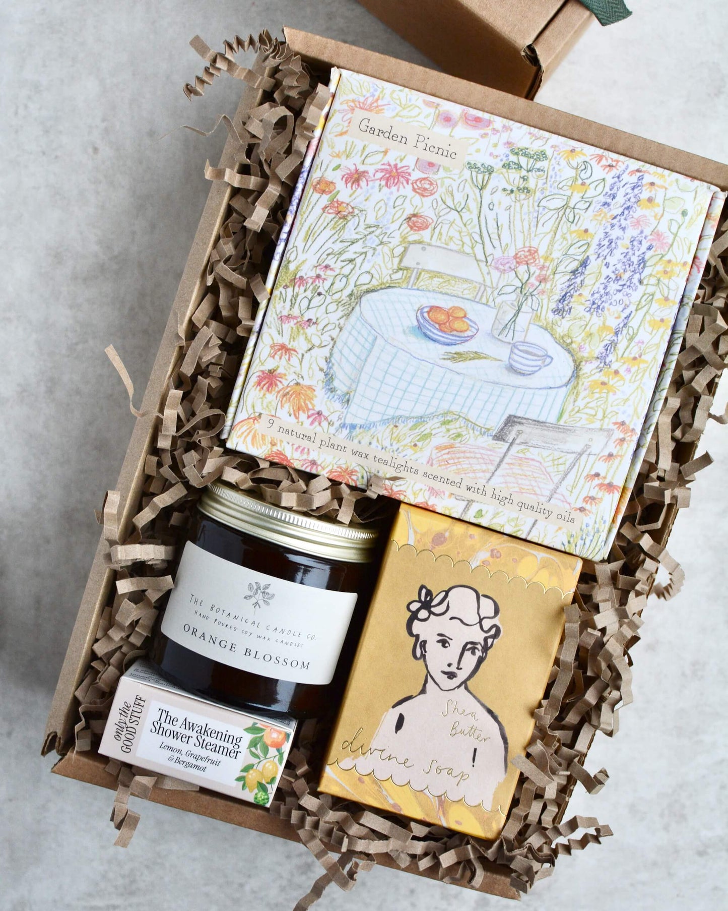 Gift box with a glass container candle, box of tealights, box of soap and a shower steamer, in bright, zesty colours.