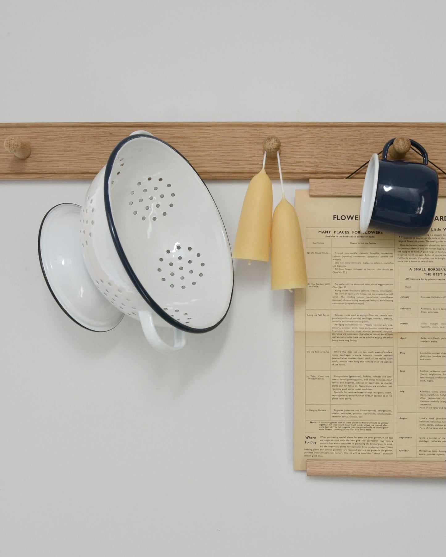 An oak peg rail, styled with candles and enamel kitchen accessories