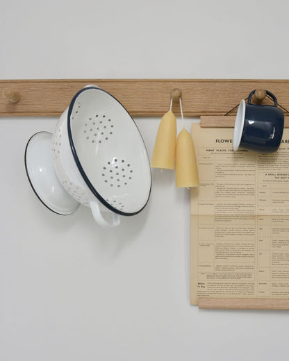 An oak peg rail, styled with candles and enamel kitchen accessories
