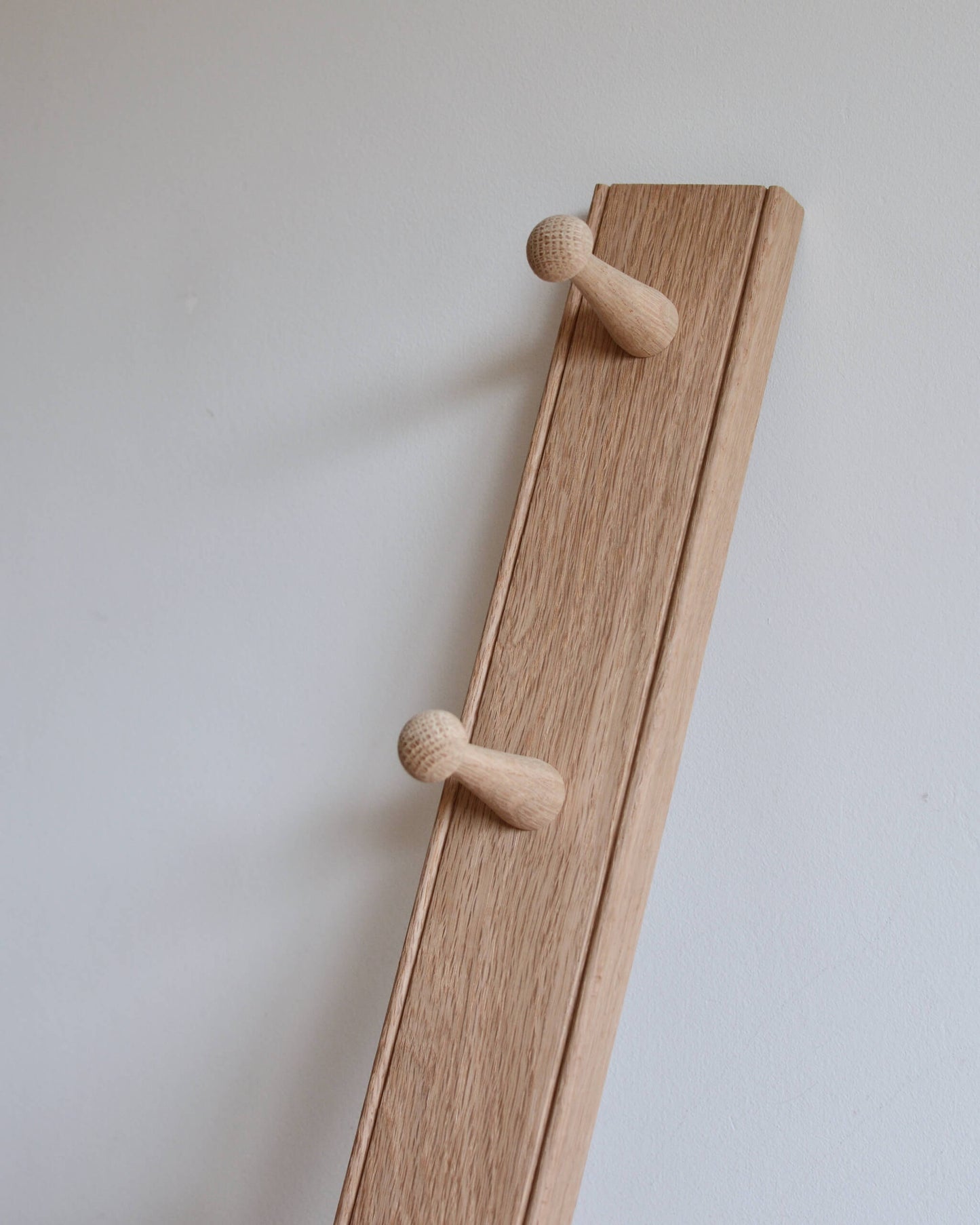 A close up of an oak shaker peg rail, showing natural oak grain