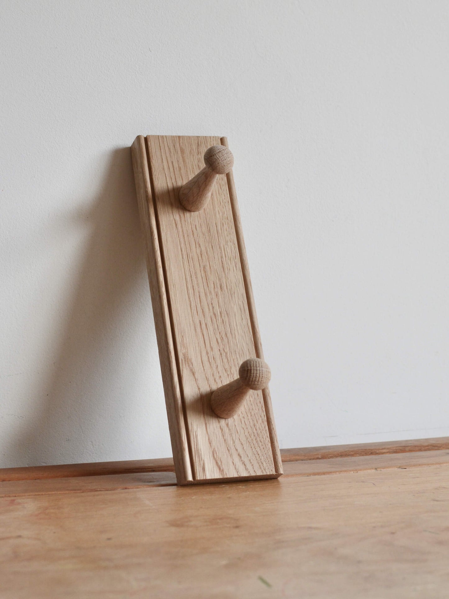 Oak shaker peg rail with 2 pegs, shown on a table