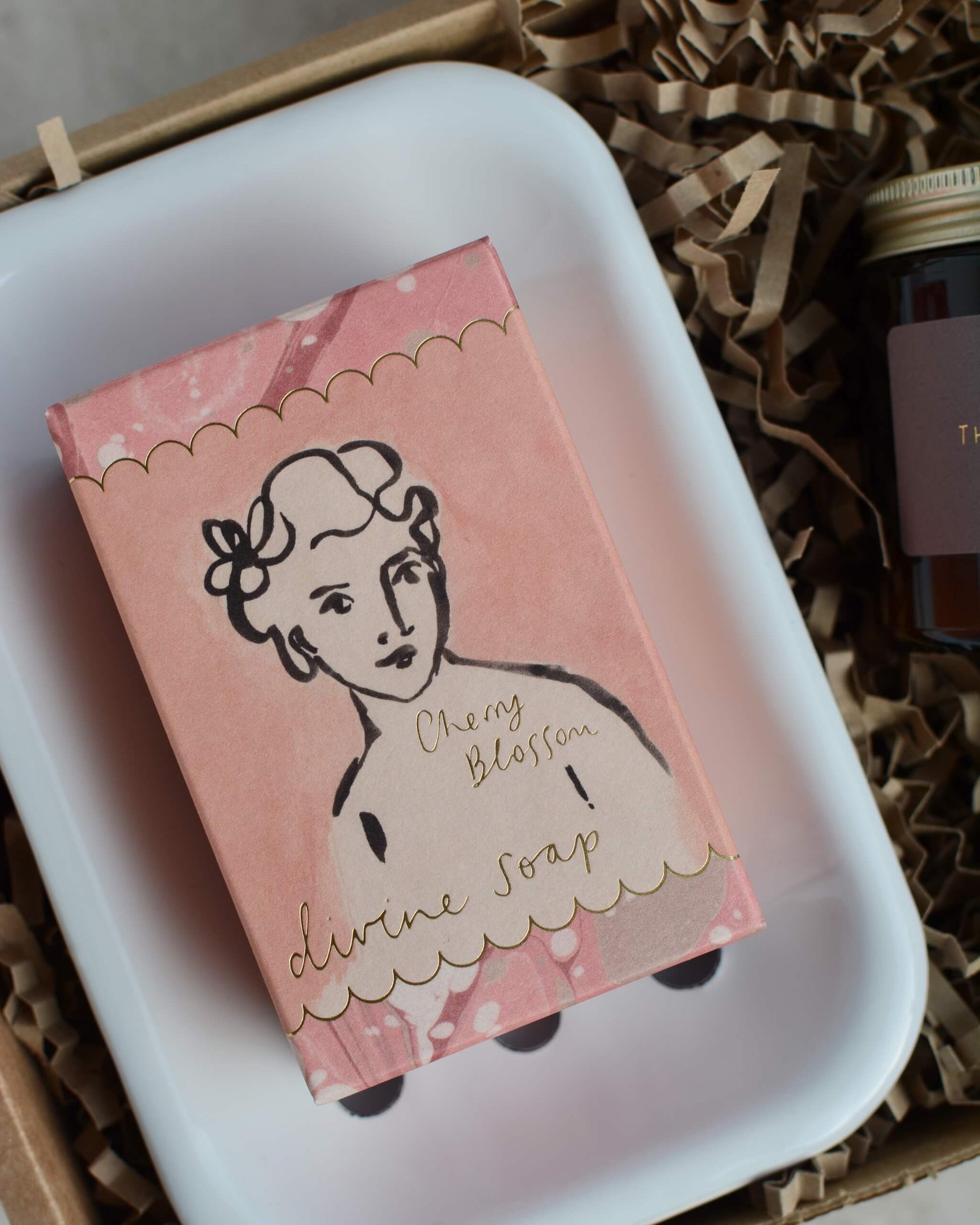 Pink soap box with a illustration of a woman on a white soap dish.