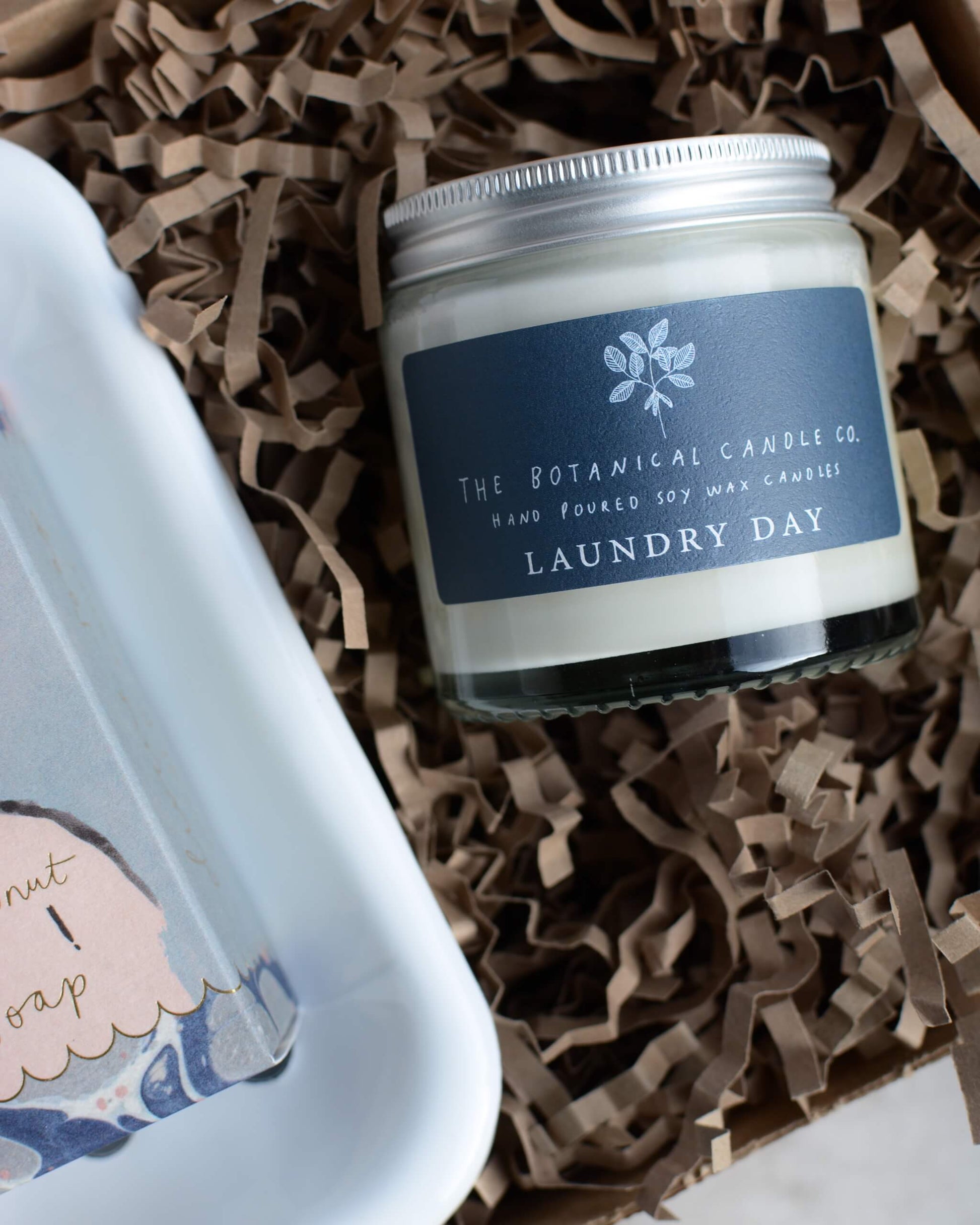 Candle jar labeled 'Laundry Day' from The Botanical Candle Co. on brown paper