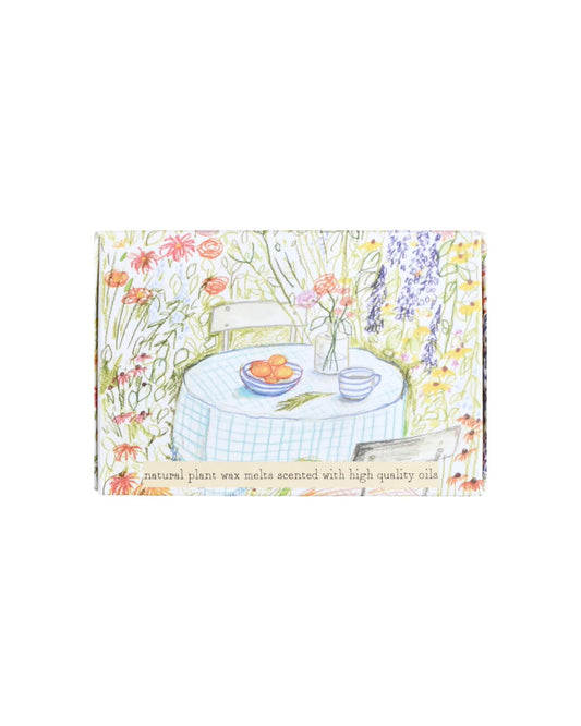 Decorative box of wax melts with a garden scene illustration featuring a table and flowers.