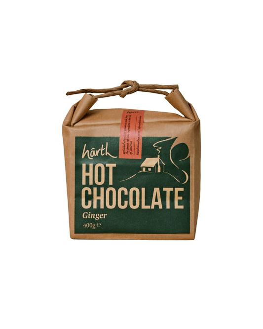 A square kraft paper package of Harth Hot Chocolate Ginger flavor, featuring a dark green front label with cream text and illustration, tied with a brown paper cord on a white background.