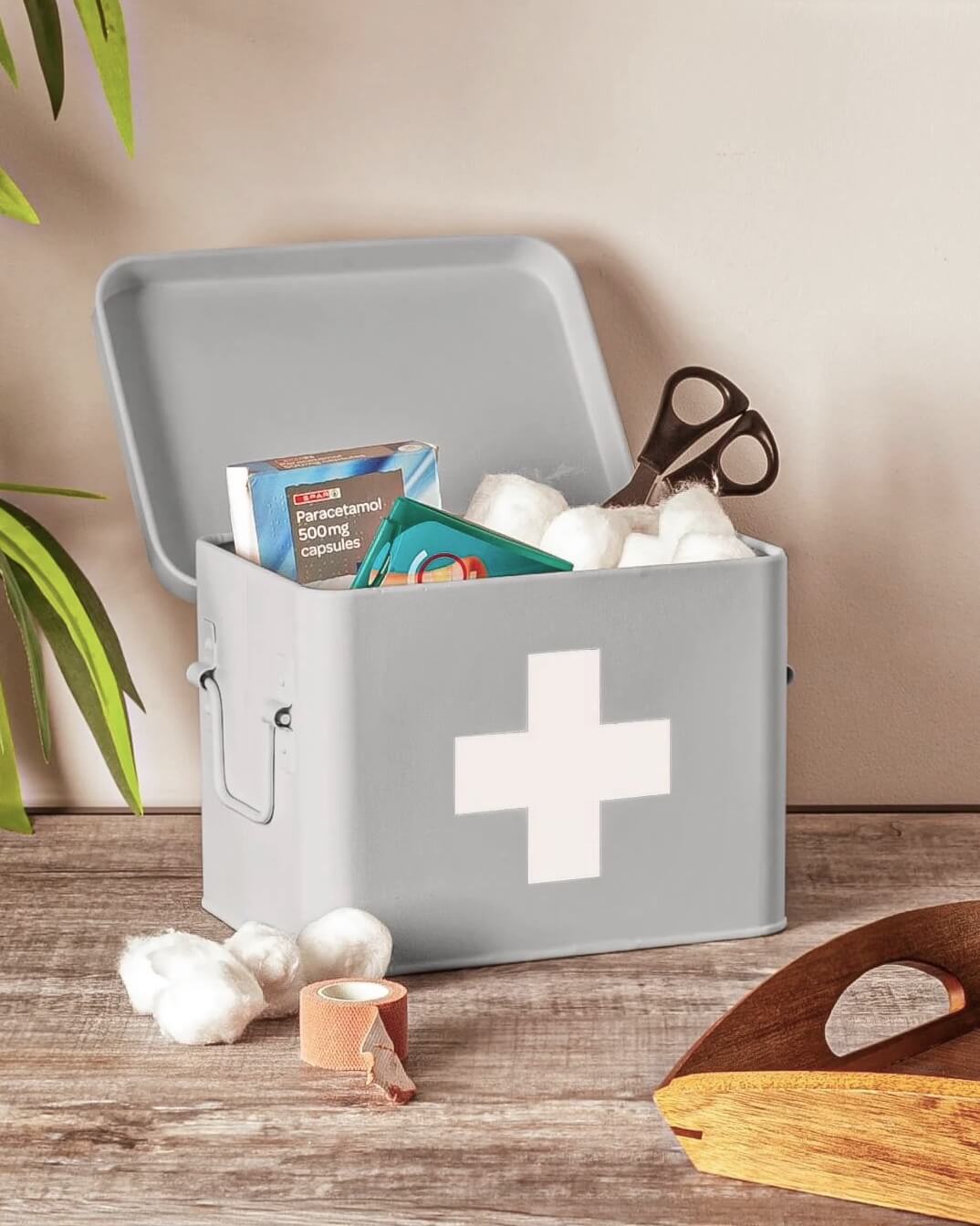 Grey metal first aid storage box open with medical supplies and plasters inside