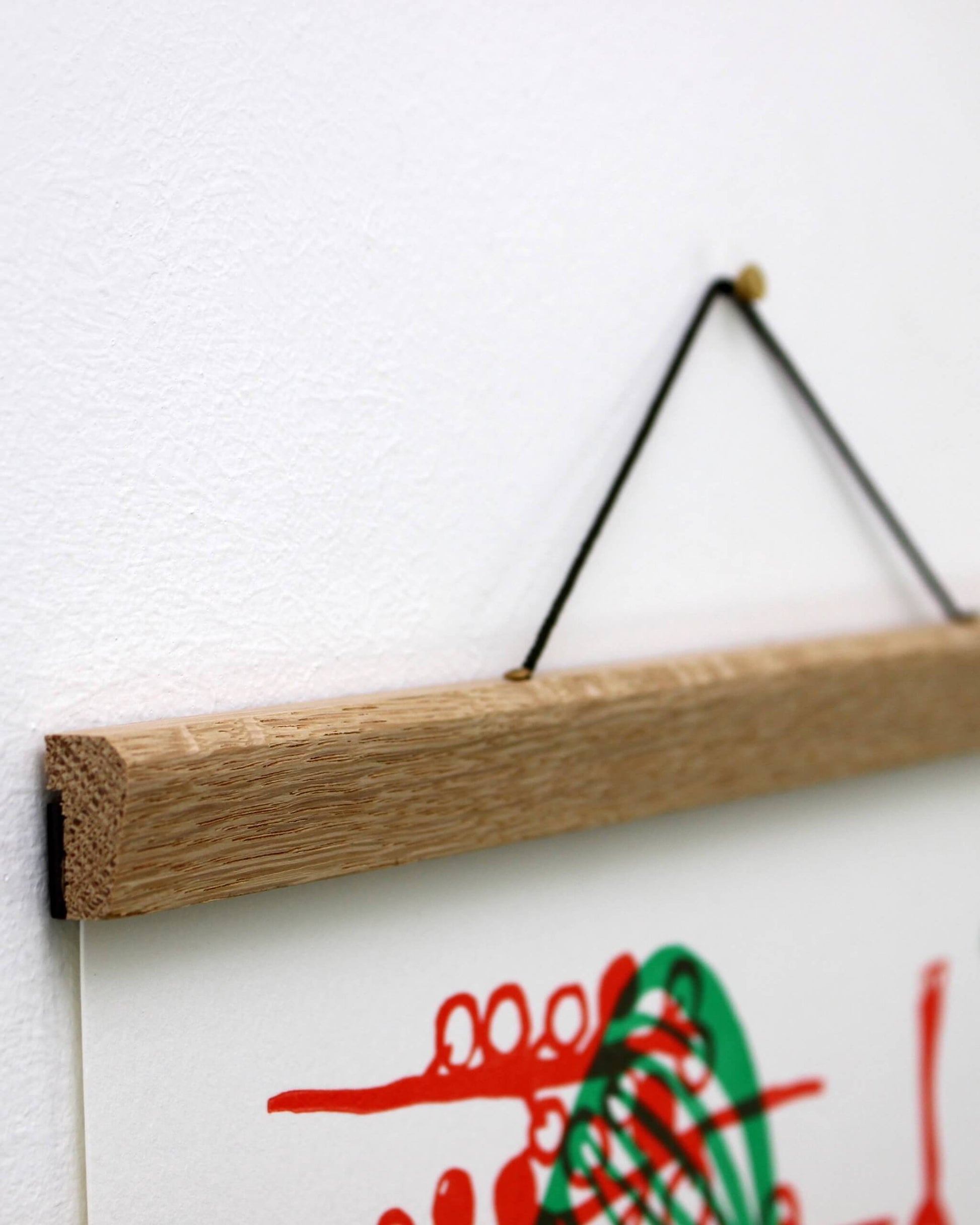Wooden poster hanger with a white background and red and green abstract design.