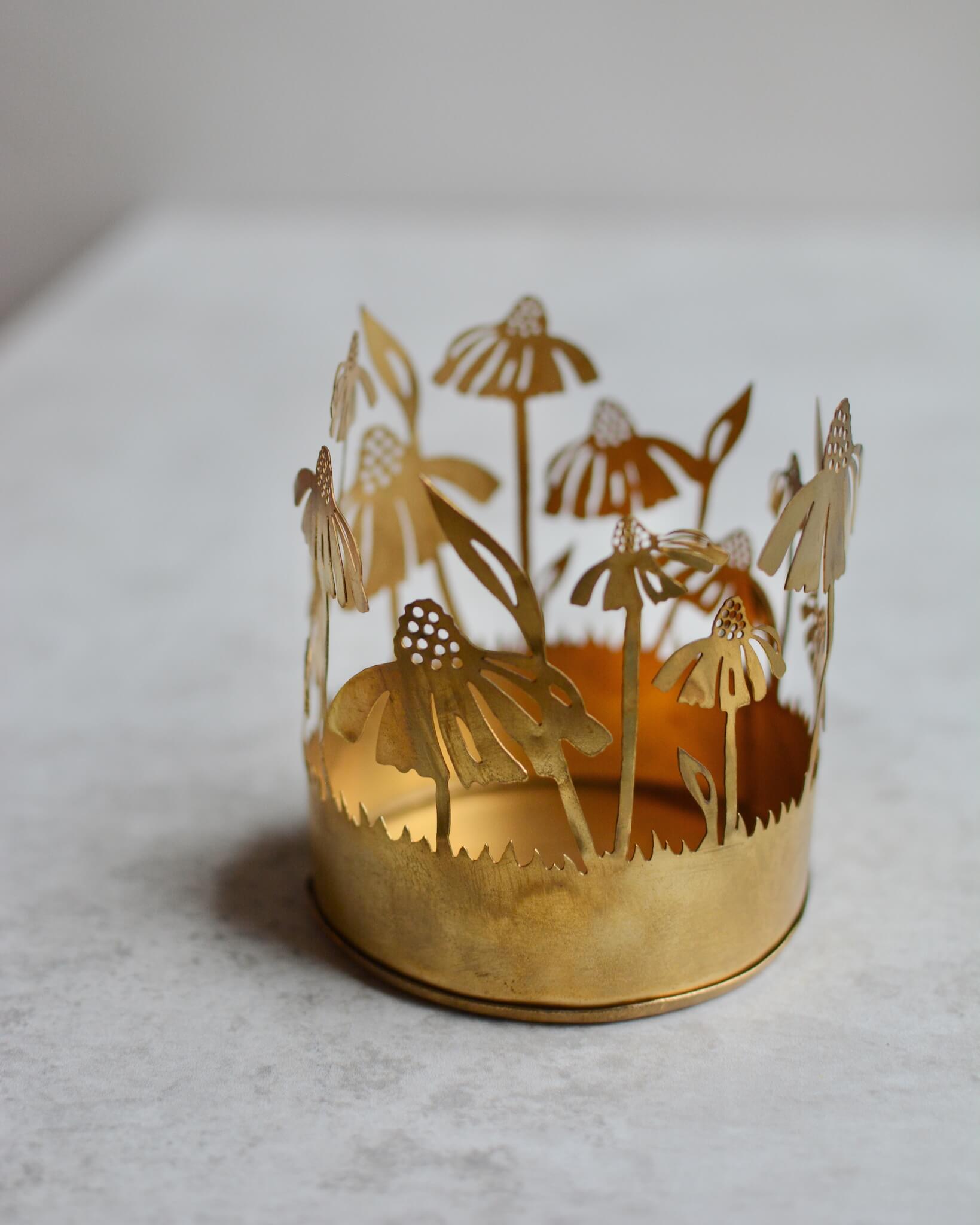 Brass tealight candle holder with floral design on a white background.